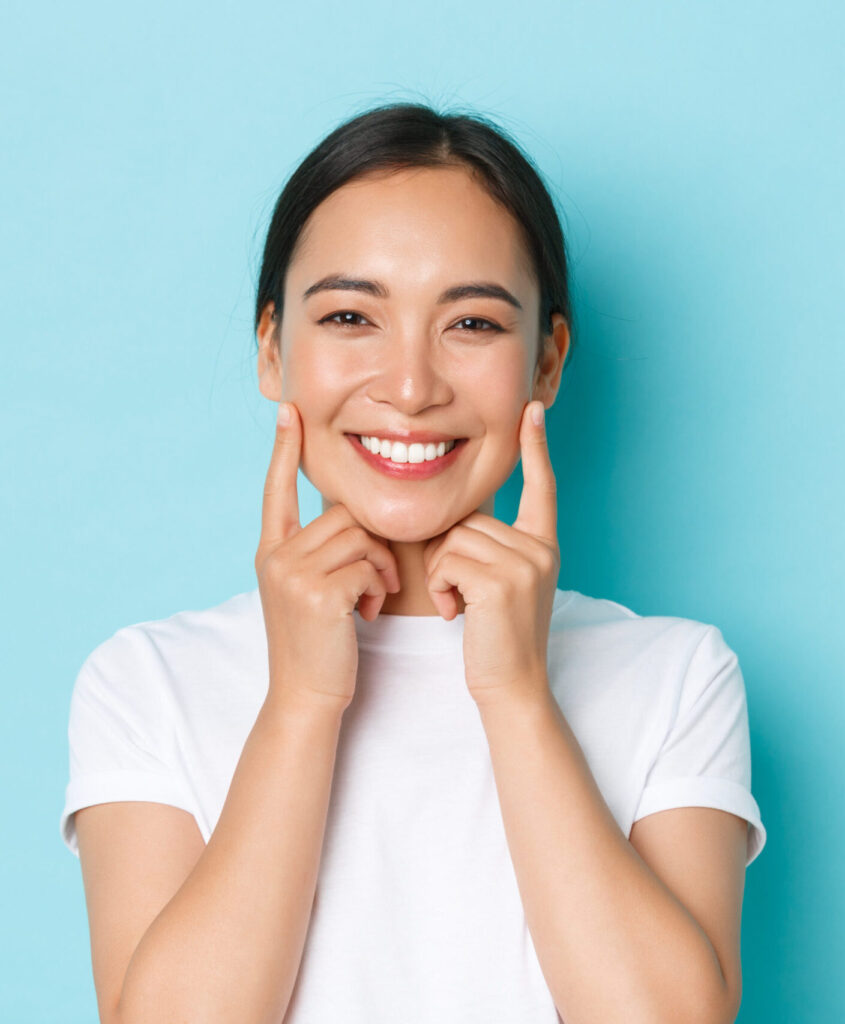 Young woman smiles and points to her teeth after treatment at Clearly Dental Camden