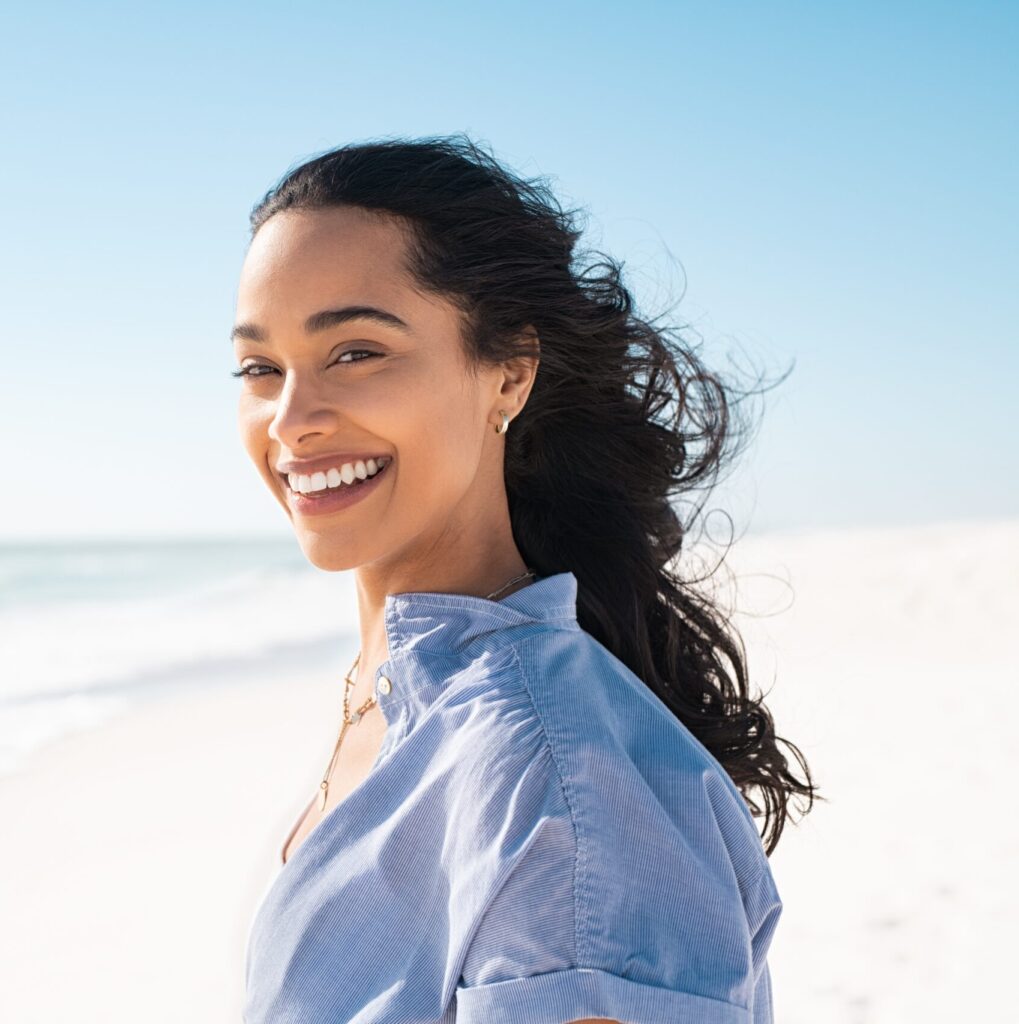 A female patient with black long hair at Clearly Dental Camden displays her bright smile after receiving dental treatment